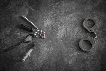 Drug syringe and cooked heroin on spoon and handcuffs . Concept - punishment for possession of narcotic drugs.