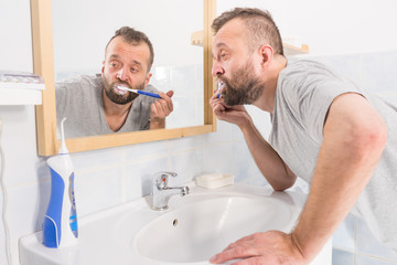 Obraz premium Man brushing his teeth in bathroom