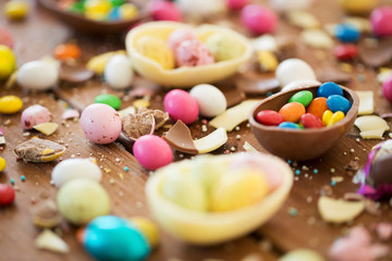 easter, junk-food, confectionery and unhealthy eating concept - close up of chocolate eggs and candy drops on table