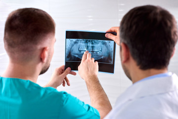 Two caucasian male dentists analyzing x-ray