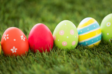 Fototapeta na wymiar easter, holidays and tradition concept - row of colored eggs on artificial grass