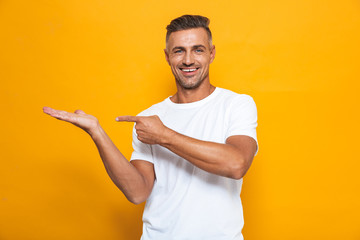 Happy excited man posing isolated over yellow wall background pointing.