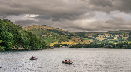 people canoeing on a lake in the lake district, with storm clouds gathering. 