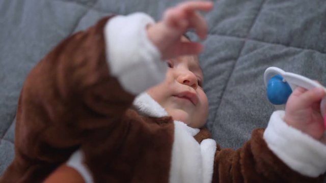 Cute baby boy playing toy. Cute child playing with rattle on bed. Sweet child portrait. Close up of lovely baby face