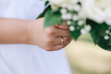 Bride holds a wedding bouquet, wedding ring, wedding details