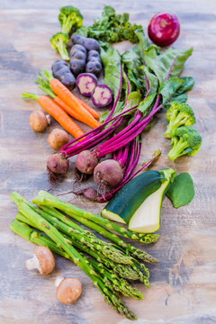 Raw and fresh spring vegetables on a wooden background.