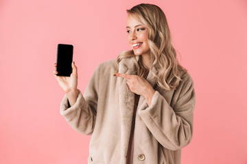 Beautiful happy young pretty woman posing isolated over pink wall background showing display of mobile phone.