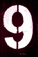 Number 9 in stencil on metal wall in pink tone.