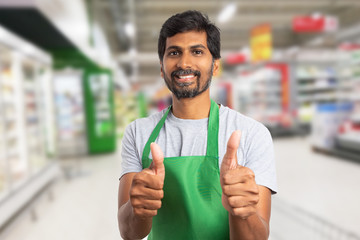 Supermarket employee making thumb-up gesture.