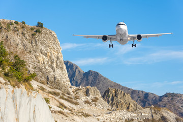 Fototapeta na wymiar Mountain landscape and landing passenger aircraft. Travel to the mountainous countries