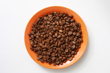 Orange saucer with coffee beans on white table