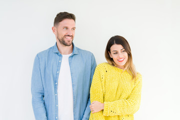 Young beautiful couple togheter over isolated background looking away to side with smile on face, natural expression. Laughing confident.