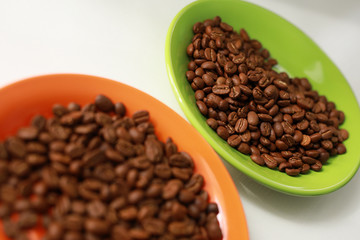 Orange and green saucer with coffee beans on white table