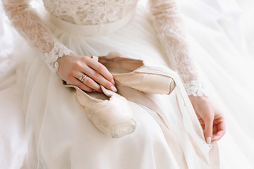 Fototapeta na wymiar Bride in elegant classic wedding dress with shoes . Morning of the bride. Ballerina with pointe shoes