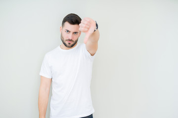 Young handsome man wearing casual white t-shirt over isolated background looking unhappy and angry showing rejection and negative with thumbs down gesture. Bad expression.