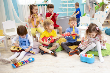Children learning musical instruments on lesson in kindergarten or preschool - 253285283