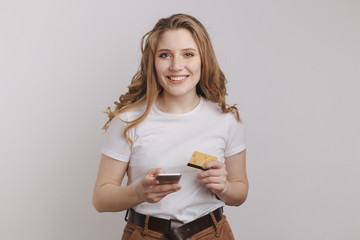 Smiling handsome model posing with her phone and credit card and making shopping online