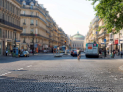Background image of center of Paris, focus on foreground. Avenue de l'Opera. People walking around, traffic on the street. Palais Garnier opera house. National Academy of Music