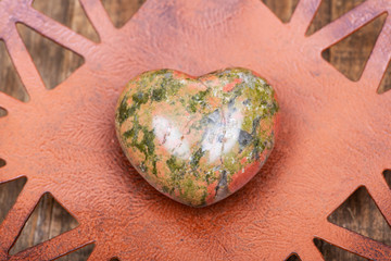Highly polished puffy Unakite Heart from Unakas Mountains in North Carolina, on Rustic Orange decorative plate.