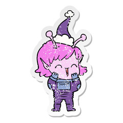 distressed sticker cartoon of a alien girl giggling wearing santa hat