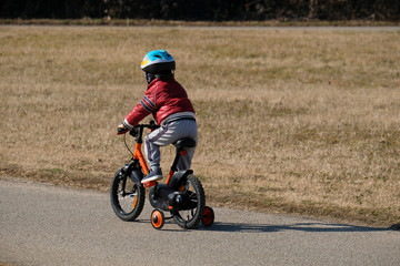little kid children with helmet playing with bicycle in a sunny day at the park - winter season.