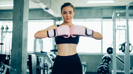 Fototapeta na wymiar Portrait of a confident young athlete woman posing in boxing gloves.Attractive Female Punching A Bag With Boxing Gloves On.