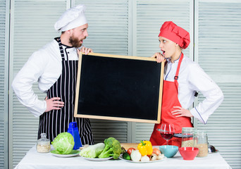 Gaining a range of skills. Couple of man and woman holding empty blackboard in cooking school. Master cook and prep cook giving cooking class. Chef and cook helper teaching master class, copy space