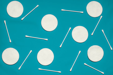 Hygiene products: round white cotton pads and cotton swabs are on colored background