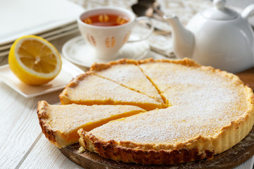 Homemade delicious lemon tart on white wooden background.