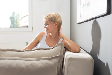 Young woman posing for a camera and smiling on sofa