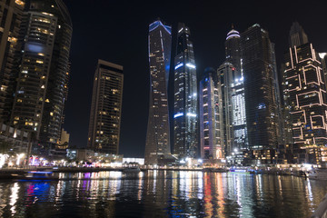 Fototapeta na wymiar Illuminated skyscrapers from Dubai Marina reflected in water during the night
