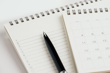 Pen with calendar and note pad with list of number for reminder, task and event planning concept