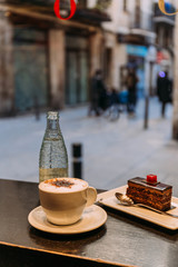 coffee cup, bottle of mineral water and saucer with cake on bar counter, barcelona, spain