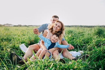 Fototapeta premium Happy family enjoying together in summer day. Family sitting on grass