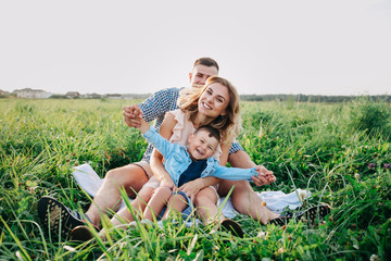 Happy family enjoying together in summer day. Family sitting on grass
