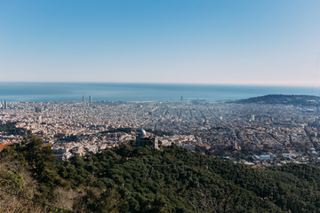 aerial view of city at foot of green hills, barcelona, spain
