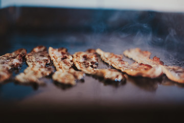 Pork bacon frying on the kitchen grill