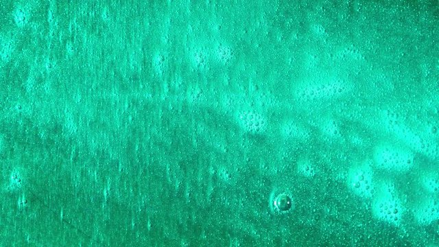 Moving colorful liquid background. Bright living liquid with paint, bubbling on surface and shimmering shiny bottom