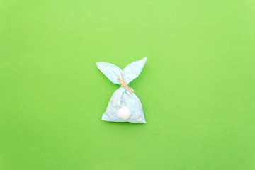 Easter bunny paper gift egg wrapping DIY idea on colorful background. Minimal easter concept, flat...