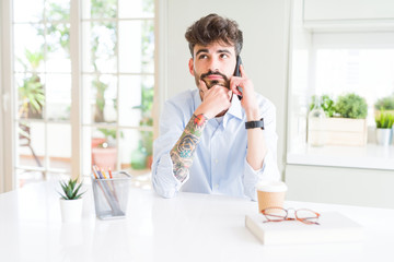 Young business man talking on smartphone serious face thinking about question, very confused idea