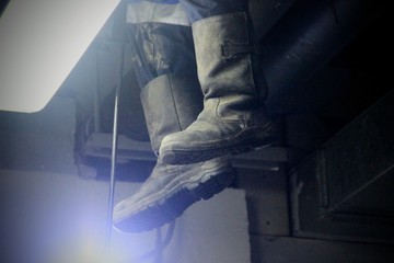 Tarpaulin boots in the light of a lantern during the works. Work of industrial clean of sewage, plumbing on the basis in the building.