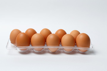 ten brown eggs in a plastic tray on a white background