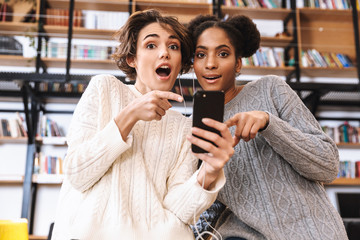 Two cheerful young girls students studying