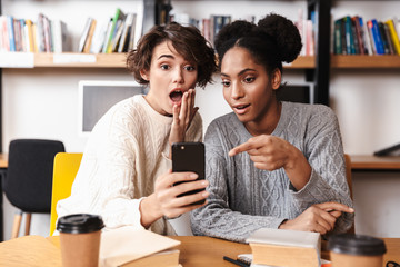 Two cheerful young girls students studying