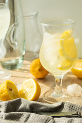 Summer refreshing drink of fresh lemon and ice cubes in transparent glass a light background. Homemade mahito or detox.