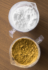 Two measuring cups with brown and white powder