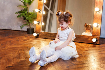 Easter celebration, pet care and animals concept. Cute happy little girl sitting on floor, holding...