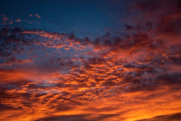 A majestic and awe-inspiration combination of deep blue sky and fiery orange and yellow clouds at sunset.