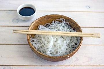 Chinese dietary noodles shirataki konjak in a wooden bowl with chinese chopsticks. Near the tape to measure the body. Gluten-free diet for weight loss.