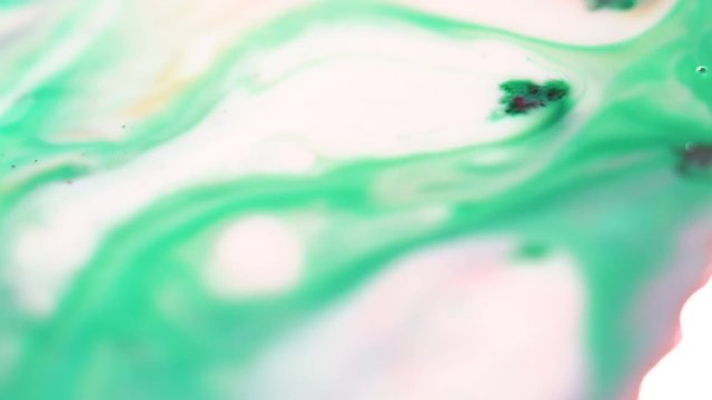 Light colored paint stains on milk. Close-up of soft colors are diluted mixing on surface of milk. Paints with milk create beautiful delicate pattern